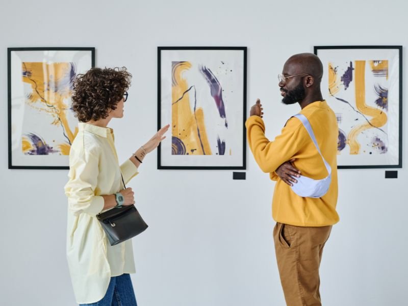 An image of a gallery wall with several abstract paintings